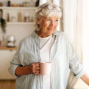 Senior woman looking out window while drinking tea