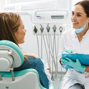 Dentist smiling while taking notes on clipboard