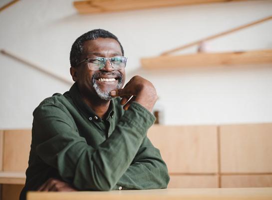 a man with glasses smiling while at home