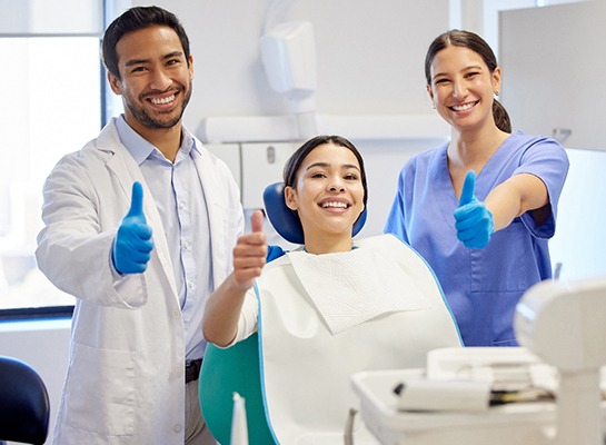 Dentist, patient, and hygienist all giving thumbs up