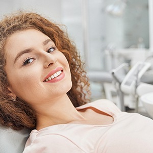 Female patient sitting back in dental chair and smiling