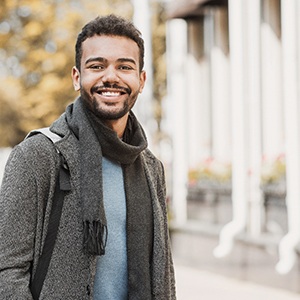 Man in scarf walking down street and smiling