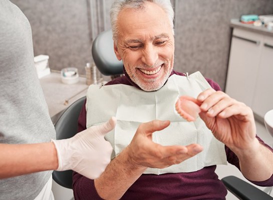 a patient smiling and receiving his full dentures