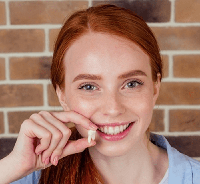 Smiling woman holding a tooth