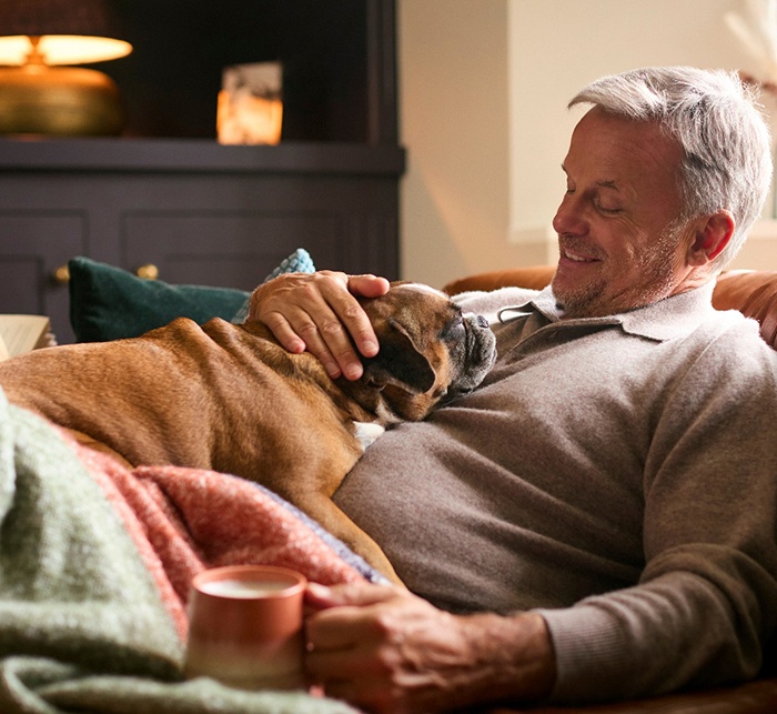 Man smiling while relaxing on couch with his dog