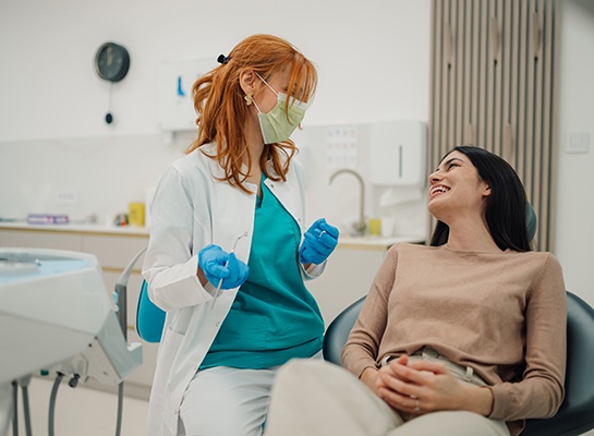 Smiling dentist and patient talking in treatment room