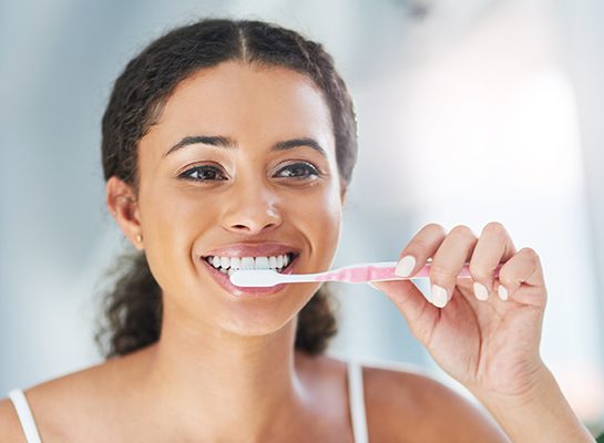 Closeup of woman smiling while brushing her teeth