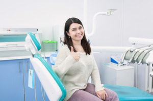 Woman sitting in dental chair giving thumbs up