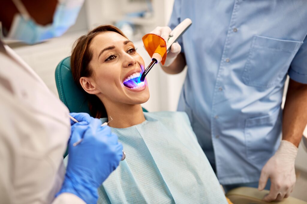 Dentist applying UV light to woman's tooth-colored filling
