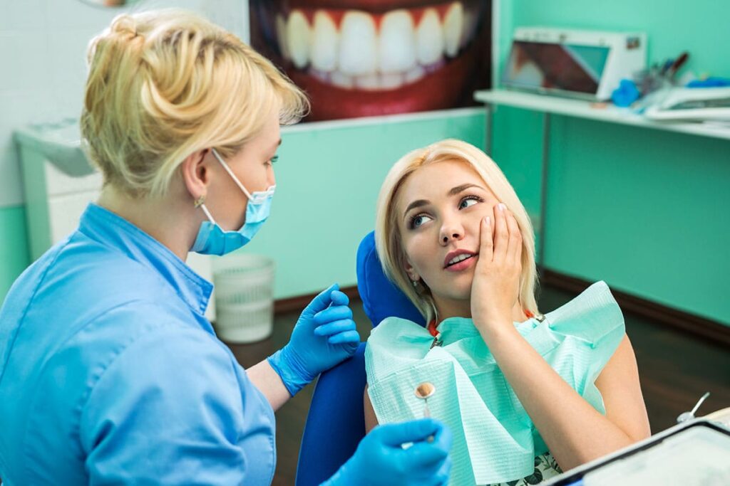 a patient sits in a dental exam chair in pain and asks her dentist what is a dental emergency