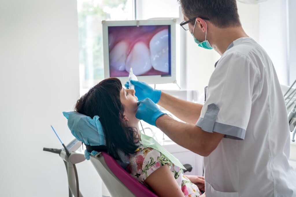 a dentist conducts a oral cancer screening on a patient sitting in a dental exam chair