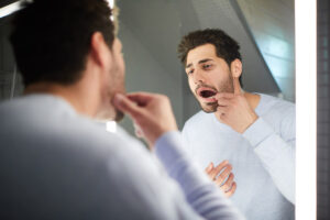 man is looking at his mouth in the mirror and wonders is periodontal disease self-treatable